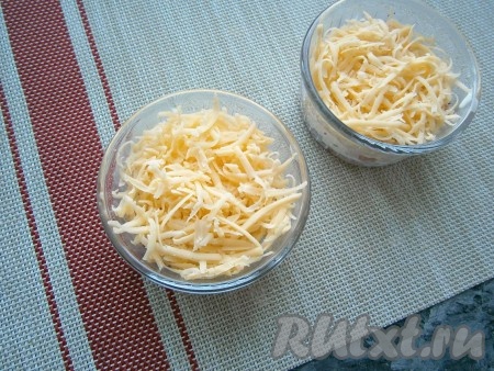 Сыр натереть на средней (или мелкой) тёрке и разложить его по кокотницам верхним слоем.
