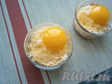 Аккуратно на сыр разбить в каждую кокотницу по одному яйцу, чтобы желтки остались целыми. Немного посолить яйца.
