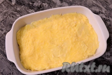 Форму для запекания (у меня размер формы 22х15 см) смазать растительным маслом, выложить картофель, разровнять его. Оставшийся натёртый сыр хорошо перемешать с ещё одним яйцом и равномерно залить этой смесью картофель сверху.

