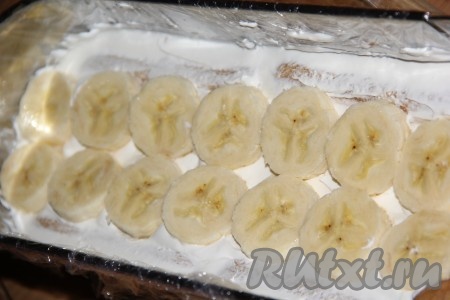 Бананы очистить и нарезать на кружочки толщиной, примерно, 7 мм. Выложить кусочки банана на крем.
