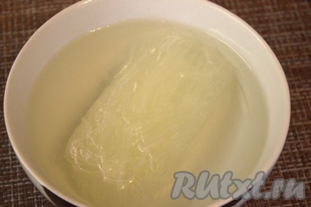 Рисовую лапшу поместить в глубокую миску, полностью залить кипятком и оставить на 10 минут.
