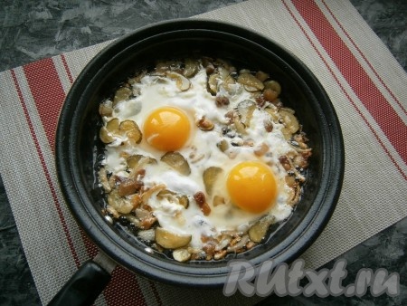 Далее разбить в сковороду 2 яйца, немного их посолить, прикрыть сковородку крышкой. Готовить яичницу с солёными огурцами и луком на медленном огне минуты 4 - пока не свернутся белки.
