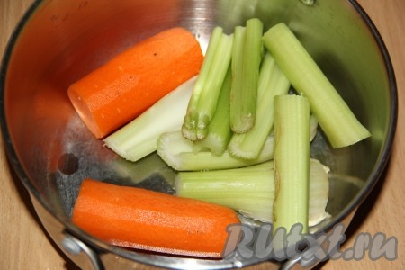 Морковь почистить и выложить в кастрюлю. Я разрезала морковь на 2 части. Стебель сельдерея вымыть, разрезать на части и тоже выложить в кастрюлю. 