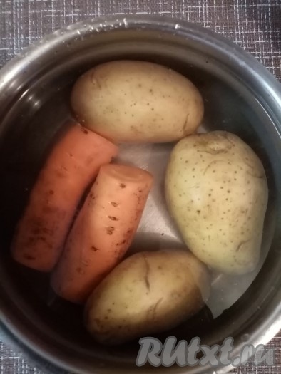 Клубни картофеля и морковь вымыть и, не очищая, поместить в кастрюлю, залить полностью водой. Накрыть кастрюлю крышкой и поставить на огонь. Варить морковку с картошкой после закипания минут 25-30 на медленном огне (готовые овощи будут легко прокалываться ножом), затем воду слить, а овощам дать остыть, очистить их. 3 куриных яйца отварить вкрутую (варить 10 минут с момента начала кипения), охладить и очистить.

