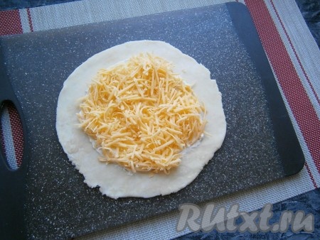 Сыр твёрдый натереть на средней тёрке, разделить на 3 равные части. Одну часть натёртого сыра выложить в центр лепёшки.
