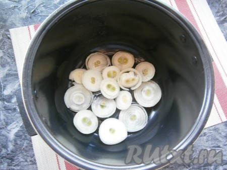 В чашу мультиварки налить 4 столовые ложки растительного масла и выложить кольца лука, полностью покрыв дно.
