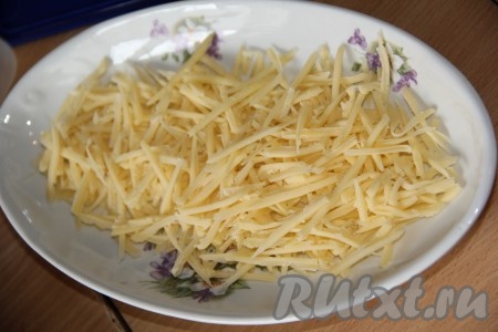 Натереть на крупной тёрке твёрдый сыр. Выложить сыр на плоскую, овальную тарелку (немного сыра отложите - он нам понадобится для украшения). 