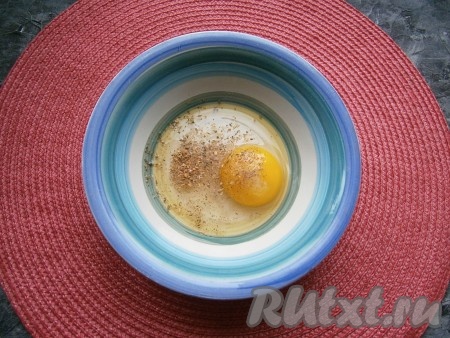 В пиалу (или миску) разбить яйцо, добавить щепотку соли, ароматные сухие травы и чёрный молотый перец.
