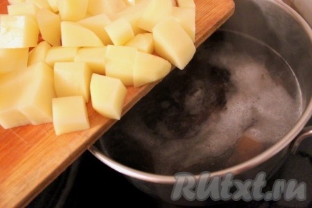 В кастрюлю для варки супа налить воду, а также грибы с грибным бульоном и добавить картофель, порезанный кубиками. Довести до кипения и варить минут 10 на среднем огне под крышкой.