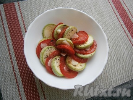 Между помидорами и кабачками разместить пластины чеснока, посолить овощи, поперчить, посыпать итальянскими травами и сушёным базиликом.
