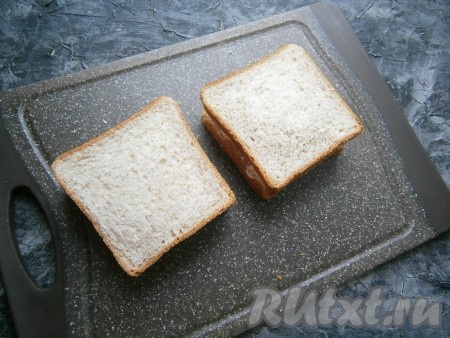 Накрыть эти два ломтя хлеба двумя ломтями хлеба с сыром, бутерброды немного придавить.