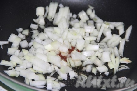 Пока варится рис, приготовим зажарку с тушёнкой, для этого нужно влить в сковороду растительное масло, выложить очищенный и мелко нарезанный репчатый лук.