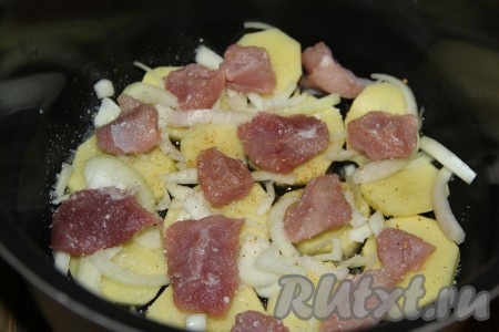 Свинину нарезать на кусочки размером 3х3 см. Часть нарезанной свинины выложить поверх картошки с луком, посолить и добавить специи по вкусу. 