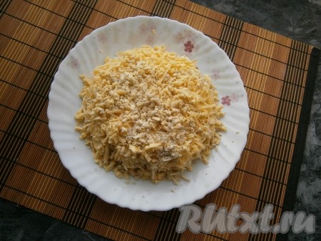 Следующим слоем выложить натёртый на средней тёрке сыр (сыром покрыть салат и с боков). На слой сыра натереть варёные желтки. 