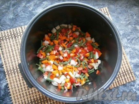 3-4 столовые ложки растительного масла влить в чашу мультиварки, выставить режим "Жарка" на 20 минут. Через 5 минут выложить в чашу перемешанные морковку, перец, стручковую фасоль, помидоры и лук.
