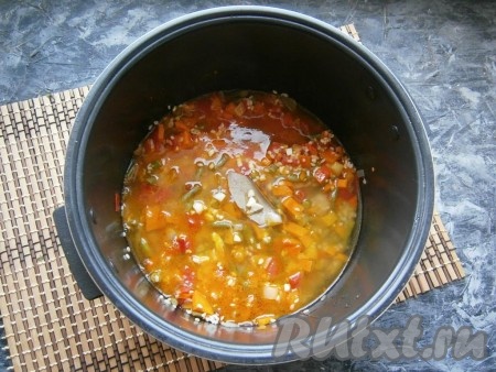 В чашу мультиварки с рисом и овощами влить горячую воду, добавить соль, нарезанный мелко чеснок и лавровый лист.
