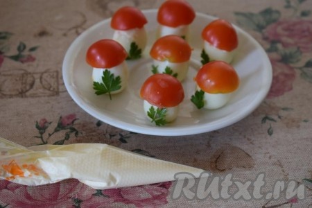 Надеть половинки помидорчиков черри на верхушки яиц, формируя "мухоморчики". Майонез переложить в кулинарный мешочек, кончик которого нужно отрезать.
