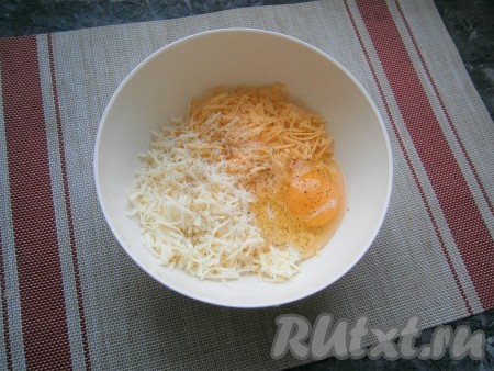 В миску с натёртым сыром добавить одно сырое яйцо, немного посолить и поперчить по вкусу, перемешать яично-сырную смесь.
