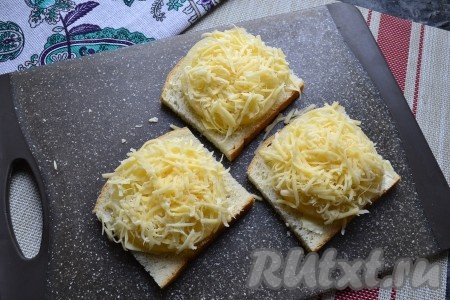 Сыр натереть на мелкой тёрке и щедро выложить его на ананасы.
