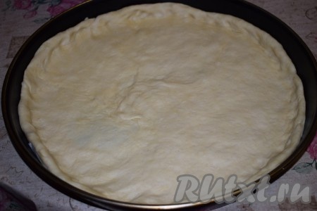На дно формы (у меня форма диаметром 42 см, можно испечь 2 пиццы меньшего диаметра) выкладываем пергамент. На пергамент кладём тесто и равномерно распределяем его по форме, формируя бортики.
