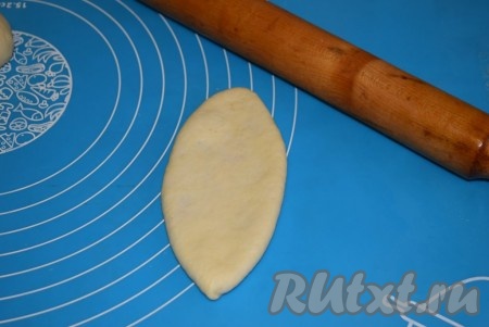 Переворачиваем пирожок швом вниз и аккуратно раскатываем его скалкой, делая плоским. Для того чтобы скалка не прилипала, перед раскаткой смазываем её растительным маслом.

