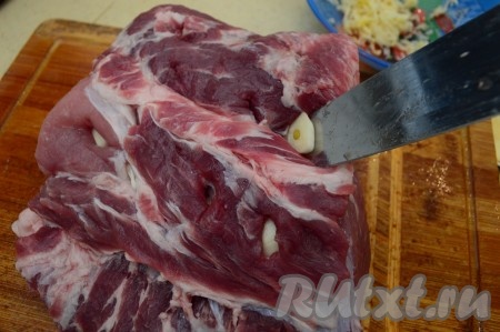 С помощью острого ножа нашпигуйте мякоть свинины со всех сторон пластинками чеснока. Не волнуйтесь, в готовом блюде не будет казаться, что чеснока много.
