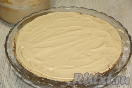Теперь можно приступать к сборке арахисового торта "Коровка". Корж выложить на подставку для торта и смазать кремом.
