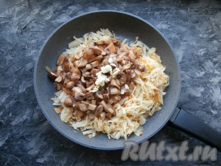 Перемешать грибы с соусом и протушить на небольшом огне несколько минут, после этого выложить в сковороду с капустой, добавить измельчённый чеснок.