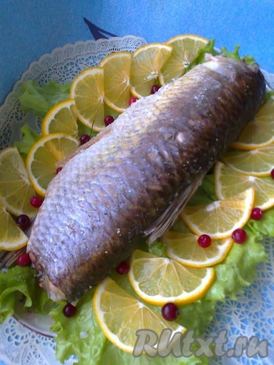 По бокам на блюдо выложить листья салата, лимон и клюкву. По середине на блюдо аккуратно выложить готовую запечённую рыбку.