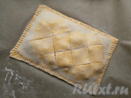 Накрыть тесто с начинкой вторым пластом теста, края тщательно залепить вилкой. Сделать несколько крестообразных надрезов сверху и смазать пиццу, по желанию, сырым яичным желтком.
