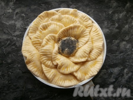 Дрожжевой пирог с творогом и яблоками прикрыть плёнкой и оставить на расстойку на 20-25 минут, после чего смазать пирог смесью из желтка и молока. Серединку посыпать маком. Пирог будет иметь вид цветка.
