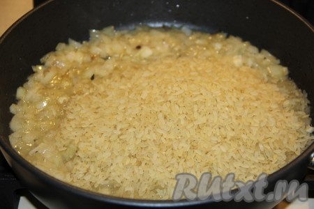 Обжарить лук до золотистого цвета, не забывая помешивать время от времени. Затем всыпать сырой рис.
