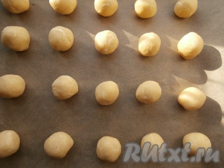Из теста скатать шарики размером чуть больше грецкого ореха, разместить их на противне, застеленном пергаментом, на достаточном расстоянии друг от друга.

