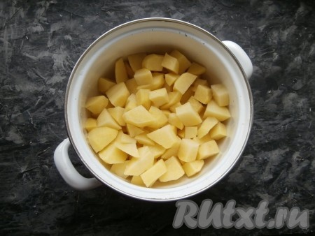 Очищенные картошины нарезать средними кубиками в подходящую кастрюлю.