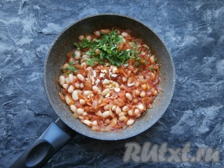 Фасоль перемешать с томатным соусом, добавить мелко нарезанный чеснок и измельчённую зелень.
