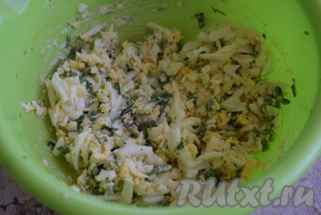 Далее готовим начинку, для этого яйца сварим вкрутую (варить нужно минут 10 с момента закипания воды), остудим и очистим. Затем натираем яйца на крупной тёрке и выкладываем в отдельную миску, добавляем мелко нарезанные зелень и зелёный лук, 1 чайную ложку майонеза, солим, перчим по вкусу и тщательно перемешиваем яичную начинку.
