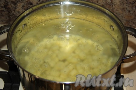 В кастрюлю влить 3 литра воды и довести до кипения. Картофель почистить и нарезать на кубики. Опустить картофель в кипящую воду.
