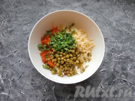 Далее в салат из отварного риса, сыра, моркови и яиц добавить консервированный зелёный горошек и измельчённый зелёный лук.
