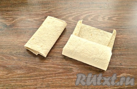 Начиная со стороны, на которую выложена начинка, аккуратно свернуть лаваш в форме конверта, подогнув края внутрь. У нас получатся 2 бутерброда из лаваша с колбасой, помидорами и сыром.
