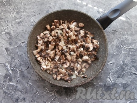 Лук обжарить на среднем огне до мягкости (в течение 4-5 минут), после этого добавить мелко нарезанные шампиньоны. Посолить грибы, поперчить, посыпать специями.
