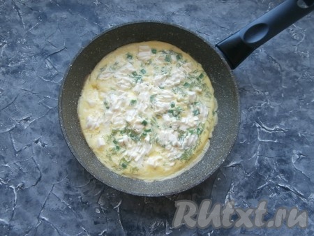 Прикрыть сковороду крышкой и готовить омлет на минимальном огне около 5-7 минут (верх омлета должен перестать быть жидким). Плавленный сыр немного размазать вилкой.