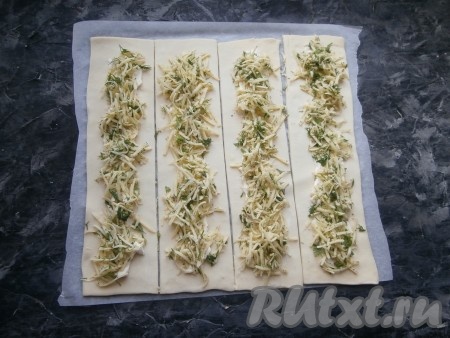 По всей длине полос выложить подготовленный твёрдый сыр, смешанный с зеленью и специями.