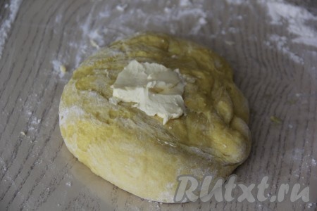 Слегка вмесить муку в тесто, а затем частями добавлять мягкое сливочное масло, каждый раз хорошо вмешивая его руками в тесто.