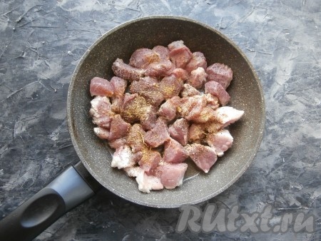 Сковороду разогреть с растительным маслом, выложить кусочки свинины, посыпать их чёрным молотым перцем и специями для мяса.
