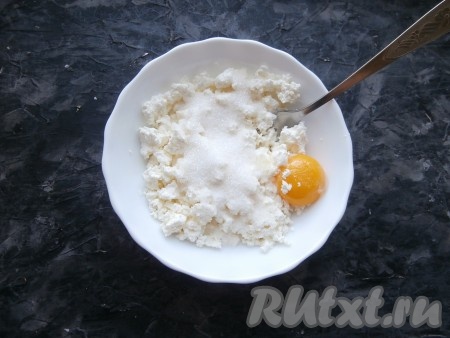 В глубокой тарелке (или миске) в творог добавить сырой желток, всыпать сахар и ванильный сахар.
