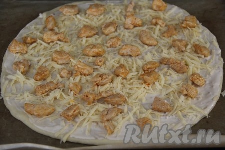 Распределить по всей поверхности пиццы кусочки курицы.