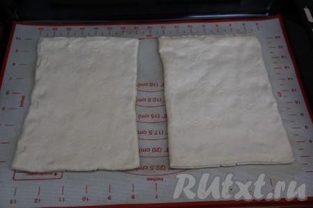 У меня слоёное тесто было в виде двух прямоугольных пластов. Тесто слегка раскатать скалкой, а затем переложить на противень, застеленный тефлоновым ковриком (или пекарской бумагой).