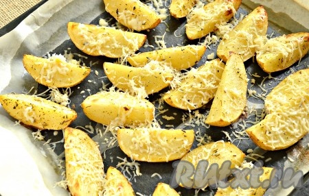 Пока картошка горячая, посыпаем её натёртым мелко сыром. В духовку возвращать картофель не нужно, сыр и так расплавится.