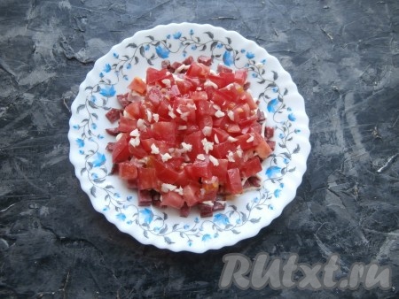 На плоскую тарелку выложить слой колбасы, смазать его немного майонезом, сверху разместить нарезанный помидор, который посыпать измельчённым чесноком.