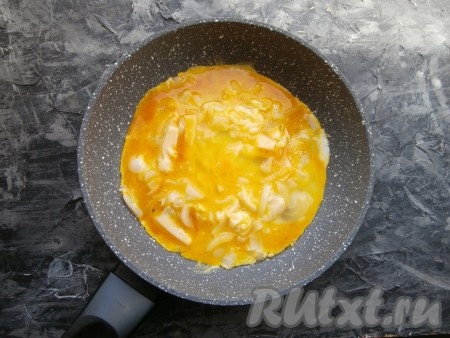 Перемешать лук с сыром и прогреть до тех пор, пока сыр не начнёт плавиться. Залить лук с сыром яйцами.